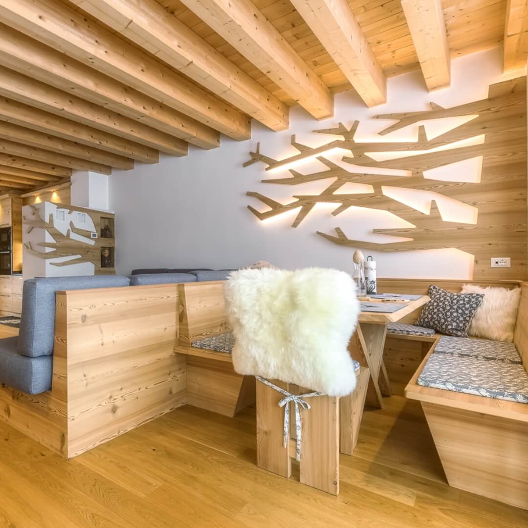 Arredamento di montagna in una sala da pranzo con panche e dettaglio di un albero