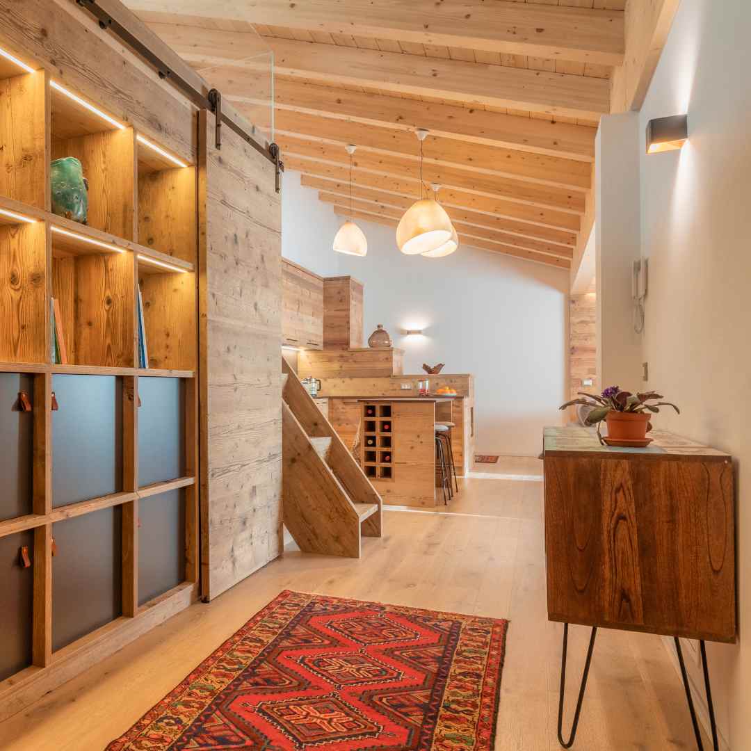 Ingresso di una casa con libreria in legno illuminata