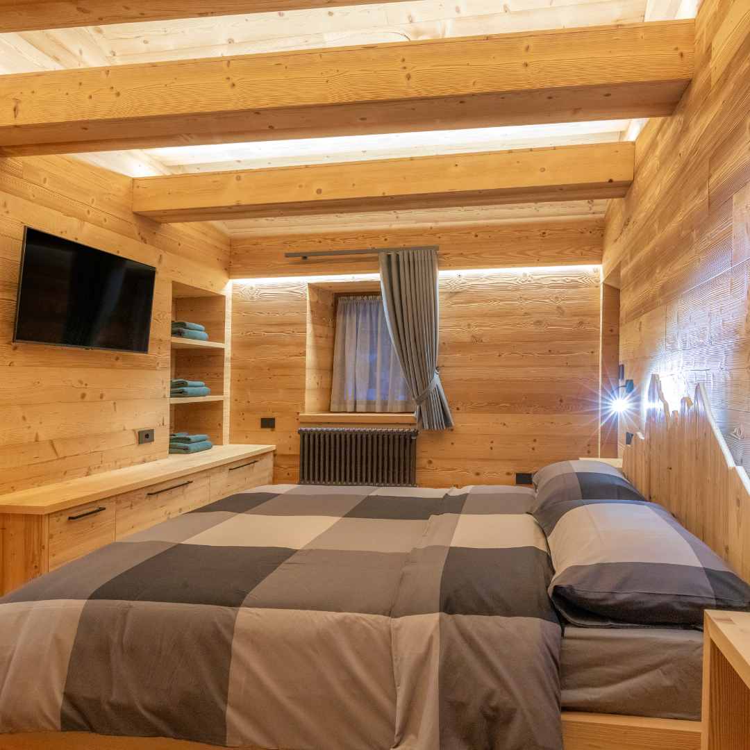 Camera da letto matrimoniale con pareti, soffitto e travi in legno