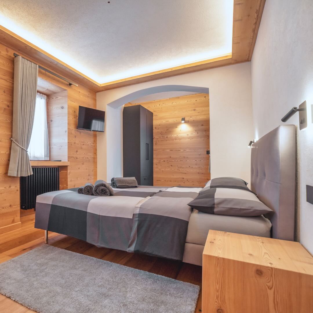 Camera da letto matrimoniale con parete, comodini e pavimento in legno