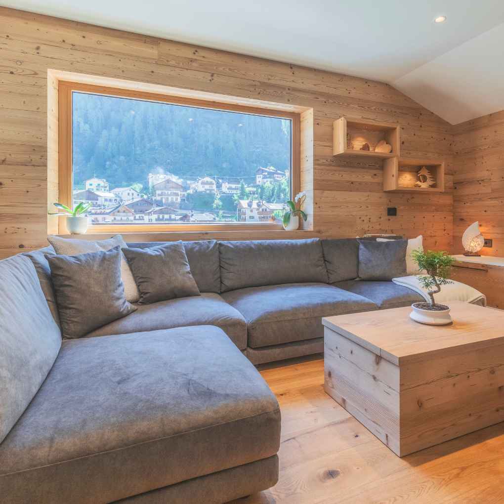 Zona giorno di montagna con divano angolare e mobili in legno naturale di abete