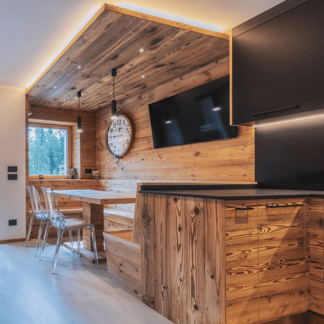 Zona pranzo cucina con panche in legno vecchio e controsoffitto con illuminazione