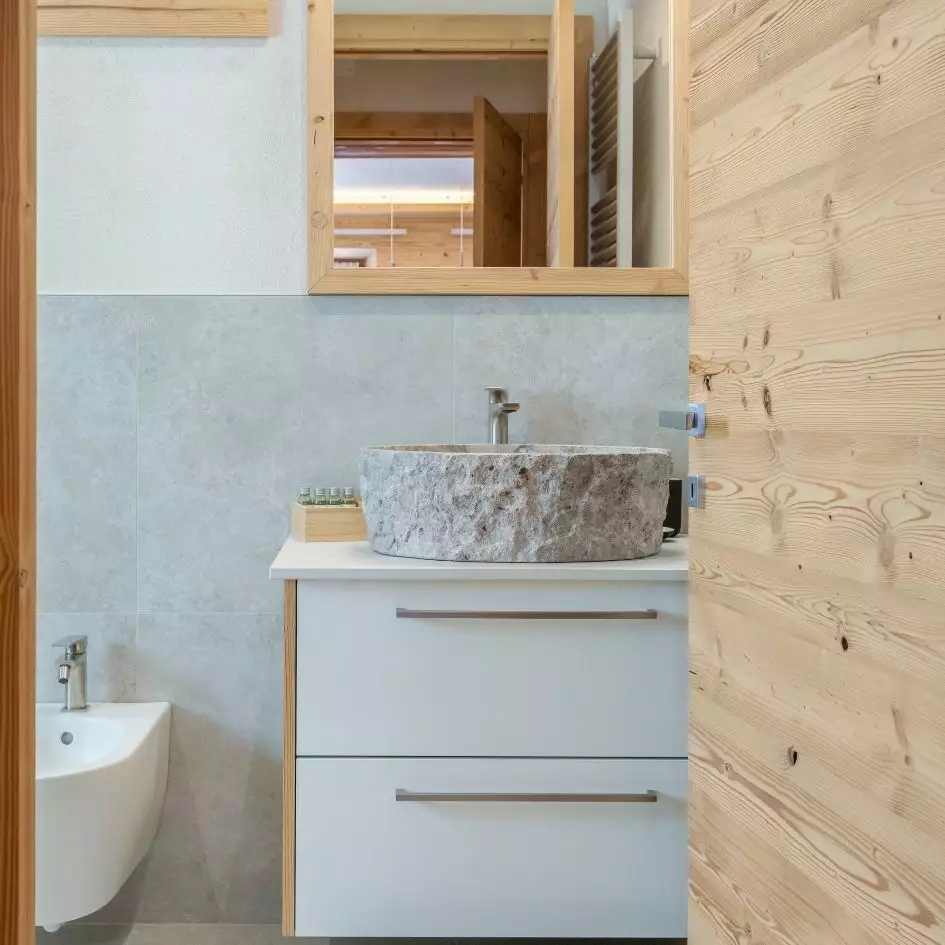 Bagno con mobile in legno e lavello di pietra